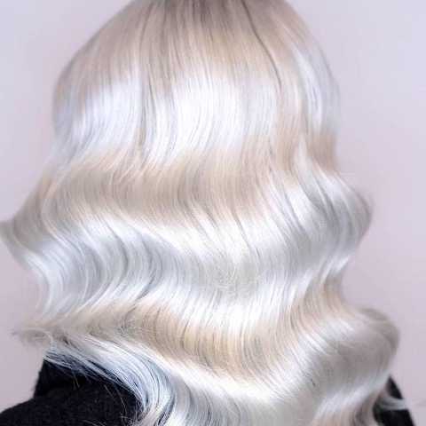 Back of woman’s head with loose, ice blonde waves, created using Wella Professionals.