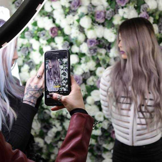 Woman taking flatlay photo on her phone of Wella Professionals products.